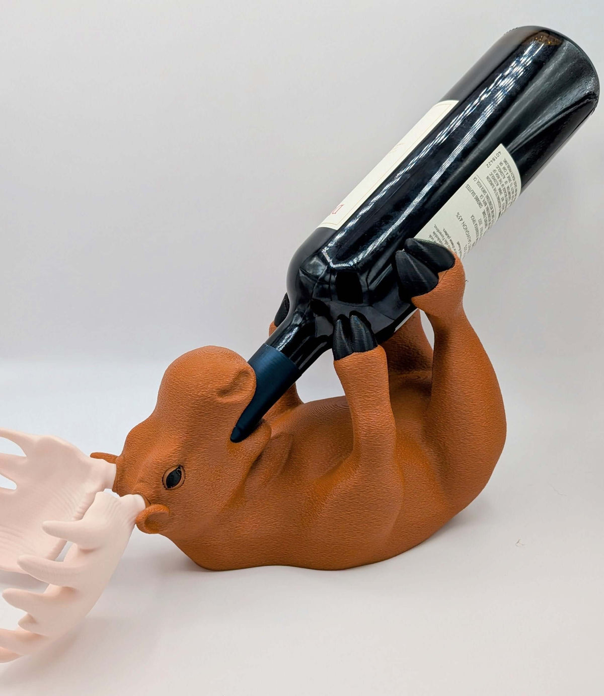 Charming 3D printed moose wine holder in a relaxed position, displaying a wine bottle upside down for playful home decor.